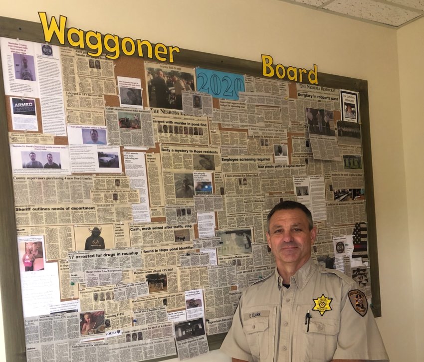 Sheriff Eric Clark stands in front of a board showcasing his office’s efforts in 2020.